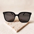 Lunettes de soleil carrées noires avec verres gris foncé sur un support en pierre - Clous de riz verticaux