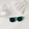 Close-up of mint green square sunglasses with dark lenses on a white lace background - Vanilla Green