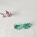 Lunettes de soleil cœur vert pour enfants avec nœud rose sur fond texturé blanc - Vert