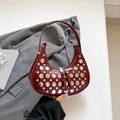 Deep red crescent moon bag with silver rivets and dual zipper detail on gray suit background - Burgundy