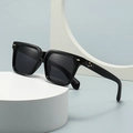 Square butterfly sunglasses with black frames and gold rivets on a white display base - Glossy Black Frame / Black Lens