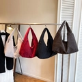 Minimalist canvas hobo bags in four colors shown hanging on a display stand - Brown
