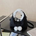 Detail of suede tote bag with white faux fur trim, black bow, and fluffy pom-pom charms - Black