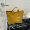 Large ginger corduroy tote bag with TOTE BAG print placed on a black stool - Brown