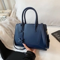 Dark blue leather tote bag with geometric stitching on white bedding background - Blue