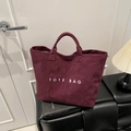 Large burgundy corduroy tote bag with white TOTE BAG text on a minimalist bench - Red
