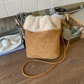 Détail de la bordure en peluche et du logo embossé sur un sac seau en daim marron - Marron
