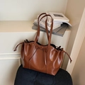 Chique bruine hoogglans PU tote bag met trekkoord en strikdetail op een stoel - Bruin
