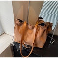 Gros plan sur un sac cabas en daim fauve avec anses en cuir et boucle métallique - Marron