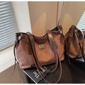 Détail du sac cabas vintage avec texture daim marron et cordons de serrage latéraux - café