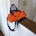 Large orange nylon tote bag with blue straps for travel and gym, shown on wooden stairs - Orange