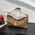 Retro brown glossy crescent underarm bag with silver metallic studs on rock background - Brown