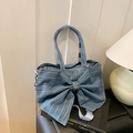 Blaue Denim-Tragetasche mit großer Schleife und Schmetterlingsanhänger auf Büchern - Hellblau