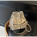 Close-up of cream leather bucket bag with silver chain strap and rivet pocket detail - Khaki
