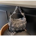 Detail of grey pleated cloud bag with textured synthetic material on a wooden stool - Gray