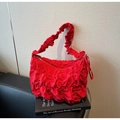 Macro shot of red ruched fabric bag with a decorative ribbon and metallic zipper puller - Burgundy