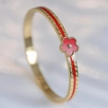 Detailed close-up of a gold-plated bangle with red enamel floral and geometric patterns - 6mm Width / Red