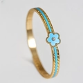 Macro detail of gold-plated bangle featuring a blue enamel flower and crystal inlay - 6mm Width / Blue