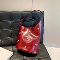 Secchiello in pelle verniciata rossa con borchie argentate su un divano nero - Rosso