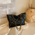 Schwarze gesteppte Shopper Tasche mit Goldkette in einem minimalistischen Studio-Setup - Mit Anhänger / Schwarz