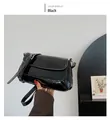 Detail of glossy black patent leather shoulder bag featuring silver metal buckle strap - Black