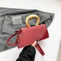 Asymmetric burgundy handbag with a bold gold circular handle and crossbody strap - Red
