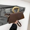 Dark brown leather handbag with melting gold handle and asymmetric geometric flap design - Coffee