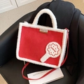 Borsa tote in peluche rossa e bianca con toppa biscotto e tracolla su una sedia - Rosso