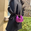 Metallisch lila Hobo-Tasche in Halbmondform mit goldener Kette auf einem Blazer - Rosa