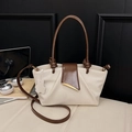 Bolso beige plisado con asas marrones y detalles dorados en un entorno de oficina moderno - Blanco Roto