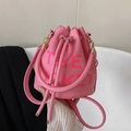Detail of pink pebbled leather bucket bag featuring The Bucket printed text and gold hardware - Rose Red