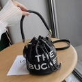 Schwarze Beuteltasche aus genarbtem Leder mit weißem THE BUCKET Aufdruck und Golddetails - Schwarz