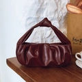 Dark brown pleated cloud bag with a unique knot handle detail on a wooden surface - Handbag Style / Red
