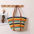 Colorful striped woven straw tote bag with brown leather straps hanging on a wooden rack - Rainbow Multicolor