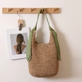 Große Stroh-Schultertasche mit grünem Band in einem minimalistischen Raum aufgehängt - Grünes Band Häkeln