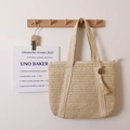 Minimalistische beige gewebte Strohtasche mit Quastenanhänger für den Strandurlaub - Beige