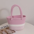 Borsa tote in cotone intrecciato rosa e bianco con manici a treccia sul tavolo - Rosa
