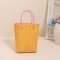 Borsa tote intrecciata a quadretti colorati con manici rosa in ambiente domestico - Giallo