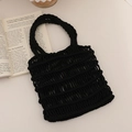 Chic black woven hollow cotton tote bag for beach vacations on a minimalist table - Black