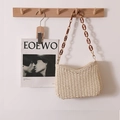 Handmade woven cream shoulder bag with brown tortoiseshell chain strap hanging on a hook - Beige