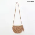 Détail du sac bandoulière demi-cercle en paille marron clair avec glands et texture tissée - café