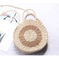Detail of a round woven straw beach bag with brown circular accent and crossbody strap - Round Beige + Camel