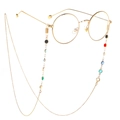 Detail of a retro gold round glass frame with colorful beaded chain on white background - Colorful Glass