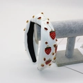Détail du bandeau noué blanc avec breloques fraises et strass brillants étincelants - Fraise