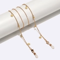 Gold metal eyewear chain with white daisy charms on a minimalist white display - Daisy Style