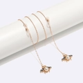 Golden eyewear chain with pearl bee pendant wrapped on a minimalist white stand - Bee Pendant Gold Style