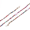 Detail van kleurrijke kralenketting voor bril met witte letterkralen en gouden karabijnsluiting - Multicolor Vierkante Letter Stijl