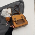 Brown leather crossbody bag with dual metal buckles and a plush teddy bear charm - Orange