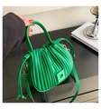 Detailed view of bright green pleated bucket bag with drawstring on black wooden table - Green