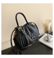 Detail view of the black pleated bucket bag with gold ring handle and hardware - Black